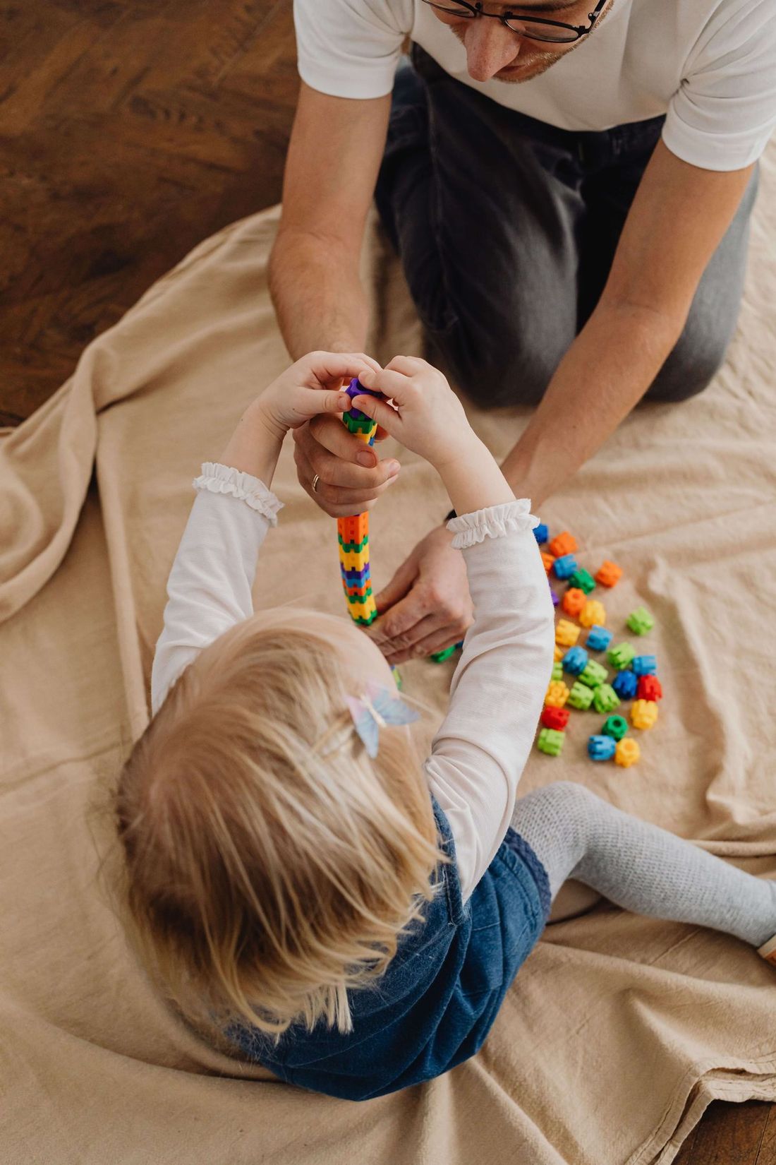 Parent and child thread colorful beads together on the floor