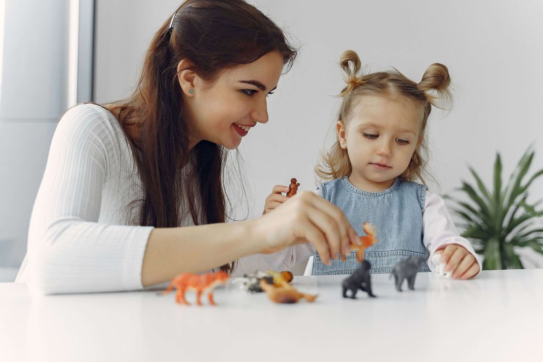 Therapist and toddler play with toy animals at a table