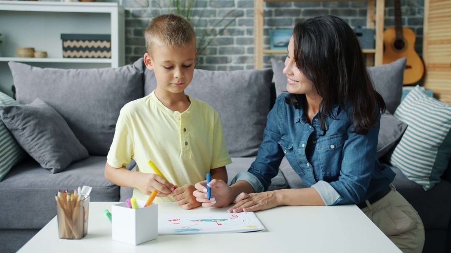 Niño en edad escolar trabaja en dibujo y escritura con una tutora en casa